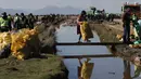 Relawan membawa kantong berisi sampah yang dikumpulkan dari Sungai Tagaret, yang mengalir ke Danau Uru Uru, dekat Oruro, Bolivia, Rabu (7/4/2021). Operasi pembersihan dimulai dalam upaya mengembalikan danau ke keindahan alamnya yang telah dibanjiri sampah plastik dan limbah lainnya. (AP/Juan Kari)