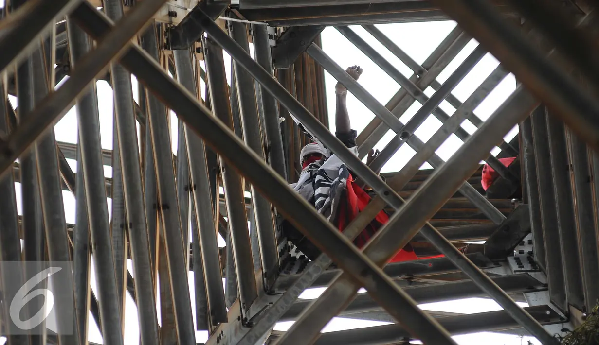 Seorang pria memanjat menara sutet di kawasan Pasar Senen, Jakarta, Selasa (27/9). Pria nekat tersebut berencana memasang bendera merah putih dengan sebuah kalimat berisi permintaan untuk menghukum oknum Dandim. (Liputan6.com/Gempur M Surya)