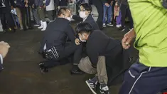 Seorang pria (di tanah) yang melemparkan apa yang tampak seperti bom asap, ditangkap di sebuah pelabuhan di Wakayama, Jepang barat, Sabtu (15/4/2023). (Kyodo News via AP)