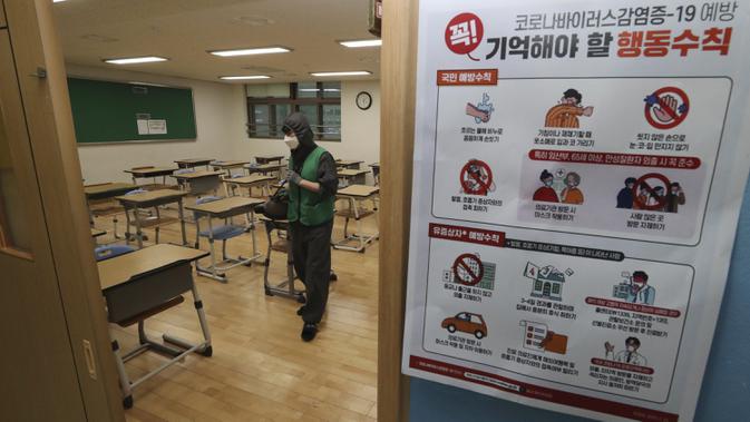 Seorang pekerja mendisinfeksi kelas di sebuah sekolah menengah di Sejong, Korea Selatan, Senin (18/5/2020. Sekolah-sekolah di Korea Selatan secara bertahap akan mulai dibuka pada 20 Mei 2020. (Kim Ju-hyung/Yonhap via AP)