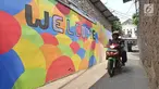 Pengendara motor melintasi gang sempit yang sisi tembok dindingnya dihiasi lukisan mural warna-warni di Kampung Pejaten, Jakarta, Senin (30/4). Mural motif warna-warni itu digagas warga untuk memperindah kampung mereka. (Liputan6.com/Herman Zakharia)