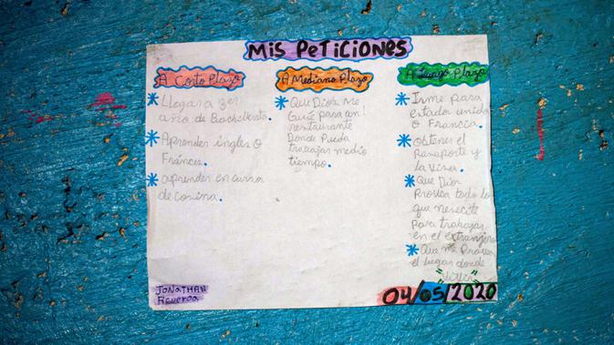 Daftar yang ditulis Jonathan Figueroa, 14, berisi harapan jangka panjang dan pendeknya ditempel di dinding rumahnya di Bello Campo, Caracas, pada 6 Oktober 2020. Di tengah pandemi, kelas dimulai lagi di Venezuela dengan siswa yang harus mencari sinyal internet di jalan. (Cristian Hernandez/AFP)