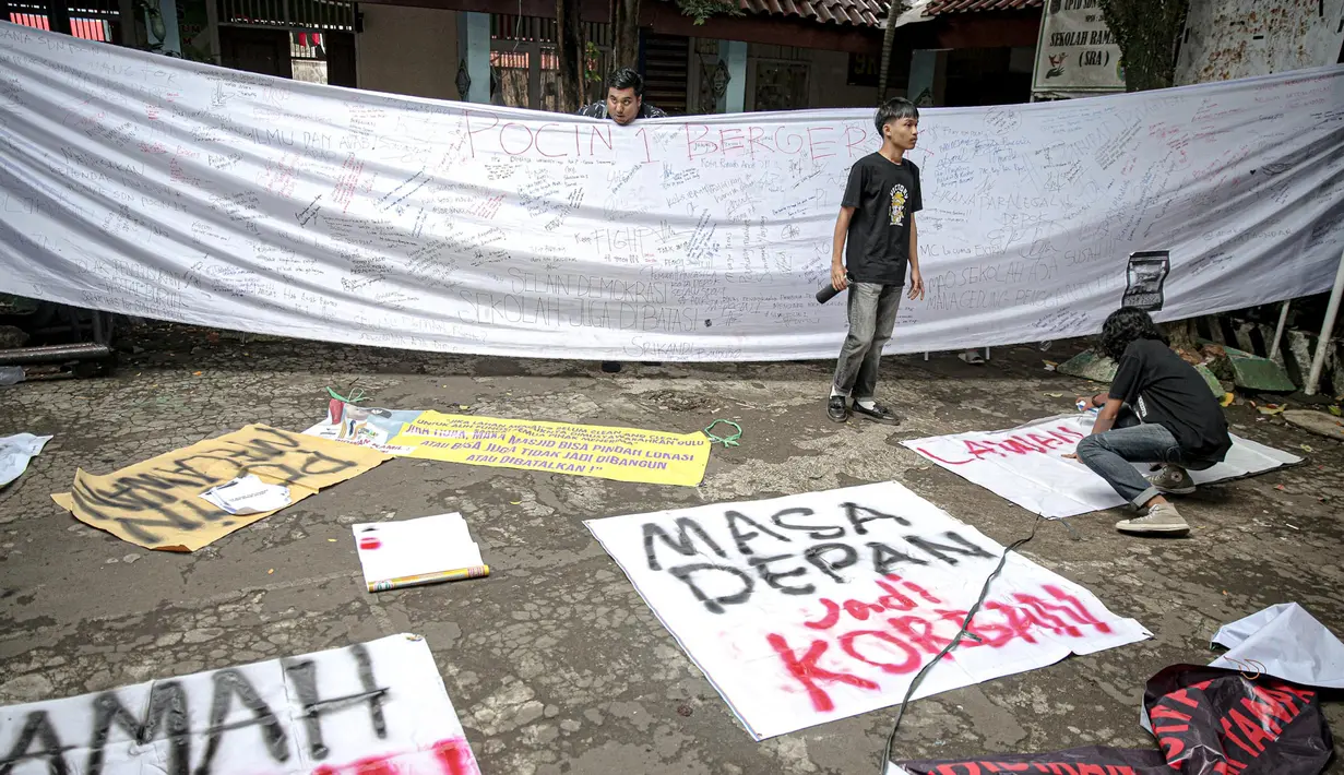 Sejumlah mahasiswa dari berbagai kampus menuliskan pesan-pesan pada spanduk saat berunjuk rasa di SDN Pondok Cina 1 Depok, Jawa Barat, Selasa (13/12/2022). Dalam aksinya, mereka menolak relokasi SDN Pondok Cina 1 yang lahannya akan digunakan untuk pembangunan masjid. (Liputan6.com/Faizal Fanani)