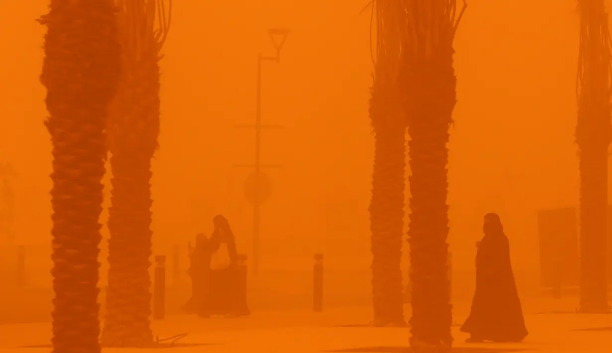 <p>Perempuan berjalan di tengah badai debu parah di Kota Kuwait pada 23 Mei 2022. Gumpalan debu besar yang melayang di atas Kuwait telah mengurangi visibilitas menjadi hampir nol di jalan-jalan hampir sepanjang hari di seluruh negeri. (Yasser Al-Zayyat / AFP)</p>