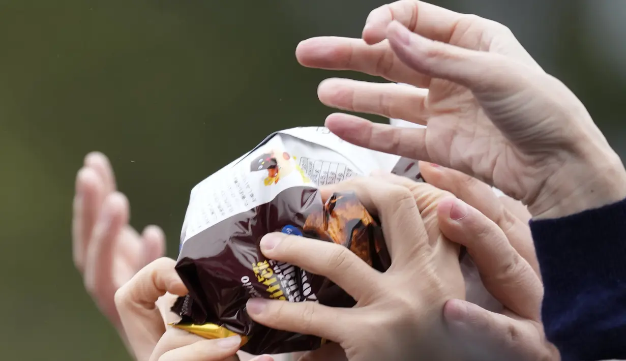 Orang-orang mencoba menangkap kacang keberuntungan yang disebarkan selama "Mame-maki", upacara melempar kacang, di kuil Buddha Zojoji, Tokyo, Jumat (3/2/2023). Warga Jepang memilih kacang kedelai panggang yang disebut fuku mame (kacang keberuntungan), yang nantinya akan dilempar keluar pintu ke arah roh jahat. (AP Photo/Eugene Hoshiko)