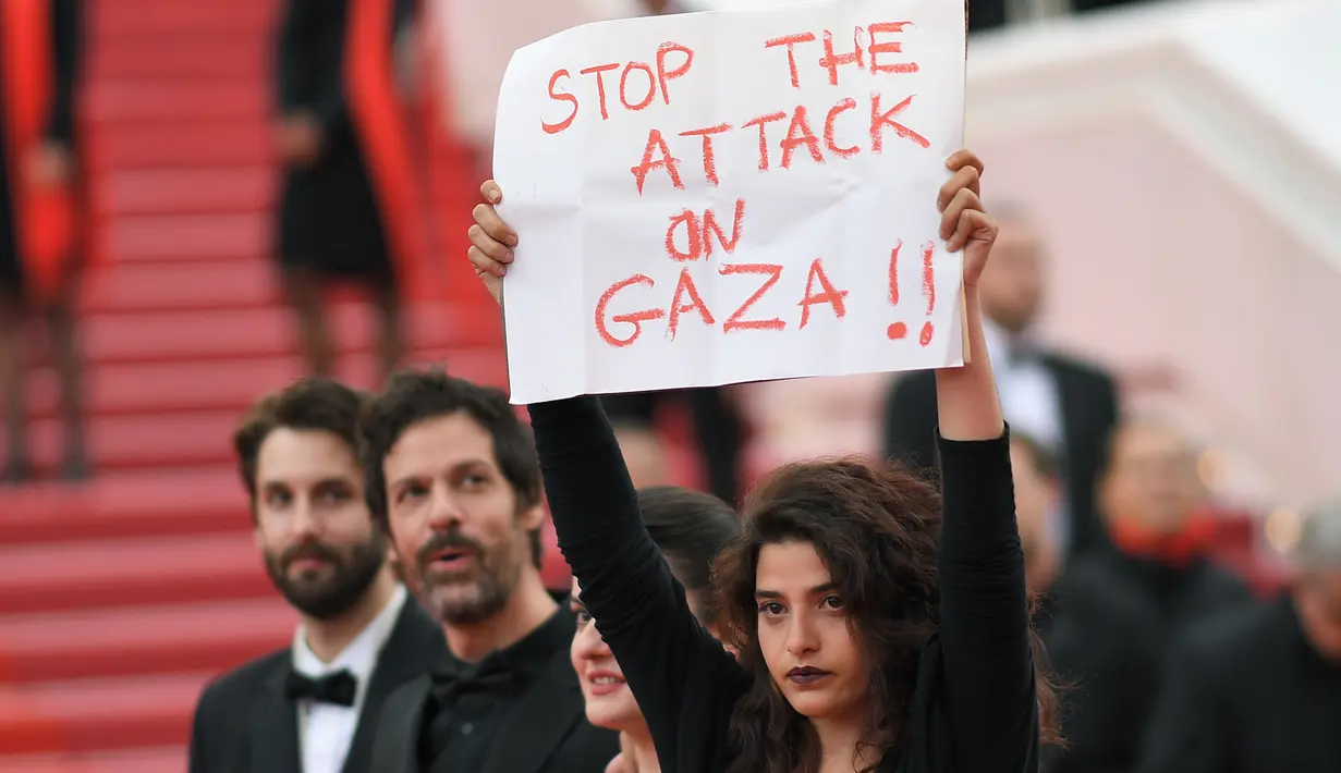 Aktris Manal Issa memegang poster bertuliskan "Hentikan Serangan di Gaza" saat menghadiri pemutaran film "Solo: A Star Wars Story" dalam Festival Film Cannes ke-71 di Cannes, Prancis (15/5). (AFP/Loic Venance)
