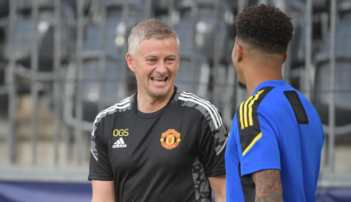 Pelatih Manchester United, Ole Gunnar Solskjaer (kiri) berbincang dengan penyerang Jadon Sancho (kanan) dalam sesi latihan di Bern (13/9/2021). Manchester United akan bertanding melawan Young Boys pada Grup F Liga Champions di Stadion Wankdorf. (AFP/Sebastien Bozon)