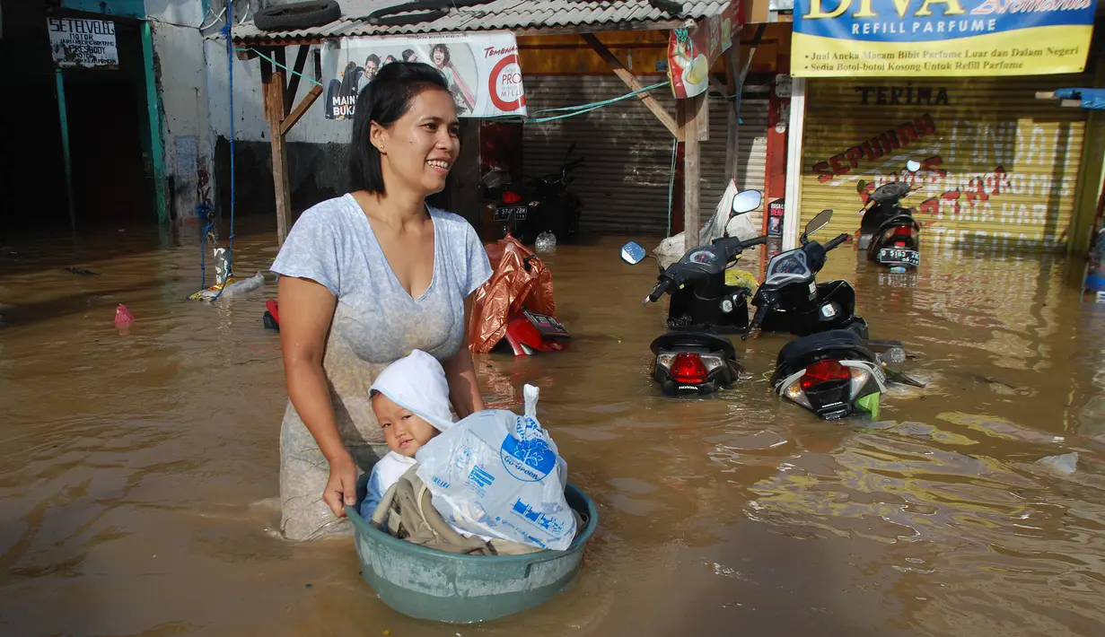 Seorang ibu membawa anaknya menggunakan ember untuk melintasi banjir di kabupaten Bandung, Jawa Barat, Minggu (13/3). Kawasan Bandung Selatan kembali dilanda banjir akibat luapan Sungai Citarum dan membuat ribuan orang mengungsi. (Timur Matahari/AFP)