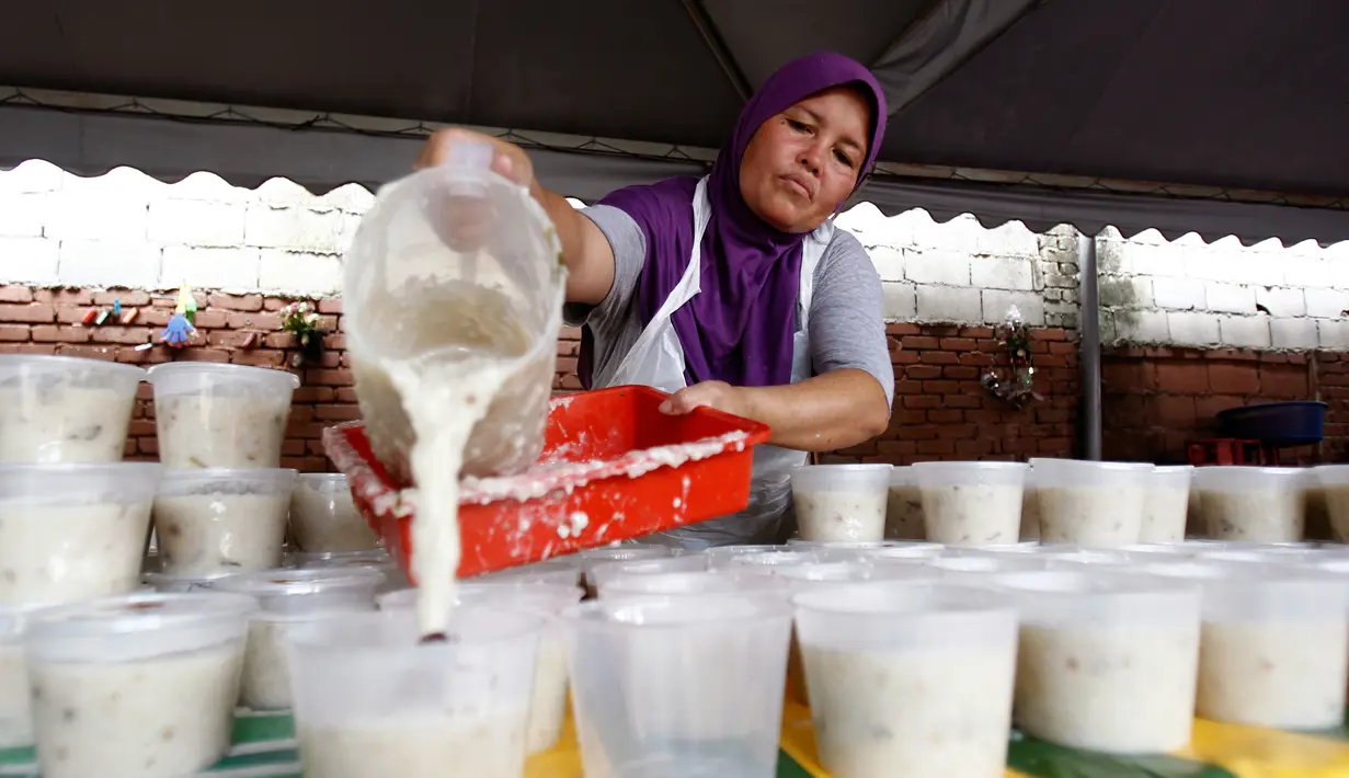 Seorang wanita menyiapkan Bubur Lambuk di desa Kampung Baru, Kuala Lumpur, Malaysia, Kamis (1/6). Bubur Lambuk adalah bubur yang terbuat dari beras dengan campuran rempah dan sayuran. (AP/Daniel Chan)