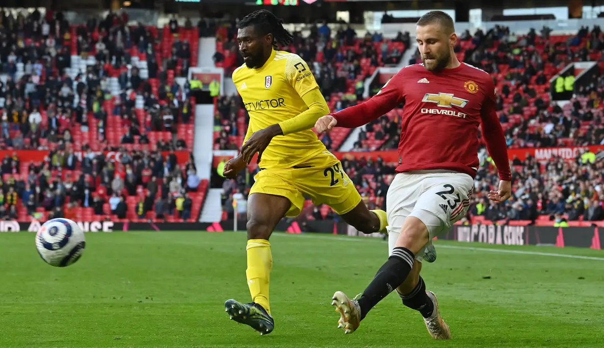 Bek Manchester United (MU), Luke Shaw mengoper bola di depan gelandang Fulham, Andre-Frank Zambo Anguissa (tengah) pada pekan 37 Liga Inggris di Stadion Old Trafford, Rabu (19/5/2021) dinihari WIB. MU kembali gagal menang setelah ditahan imbang 1-1 oleh tamunya Fulham. (Paul ELLIS/POOL/AFP)