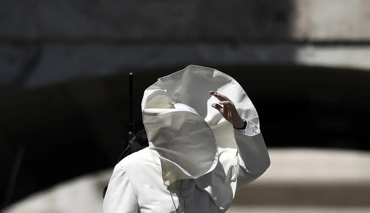 Embusan angin menyebabkan wajah Paus Fransiskus tertutup jubahnya sendiri saat memberkati umat setelah misa pada pertemuan dengan para pemuda di Lapangan Santo Petrus, Vatikan, Minggu (12/8). (AFP PHOTO / FILIPPO MONTEFORTE)