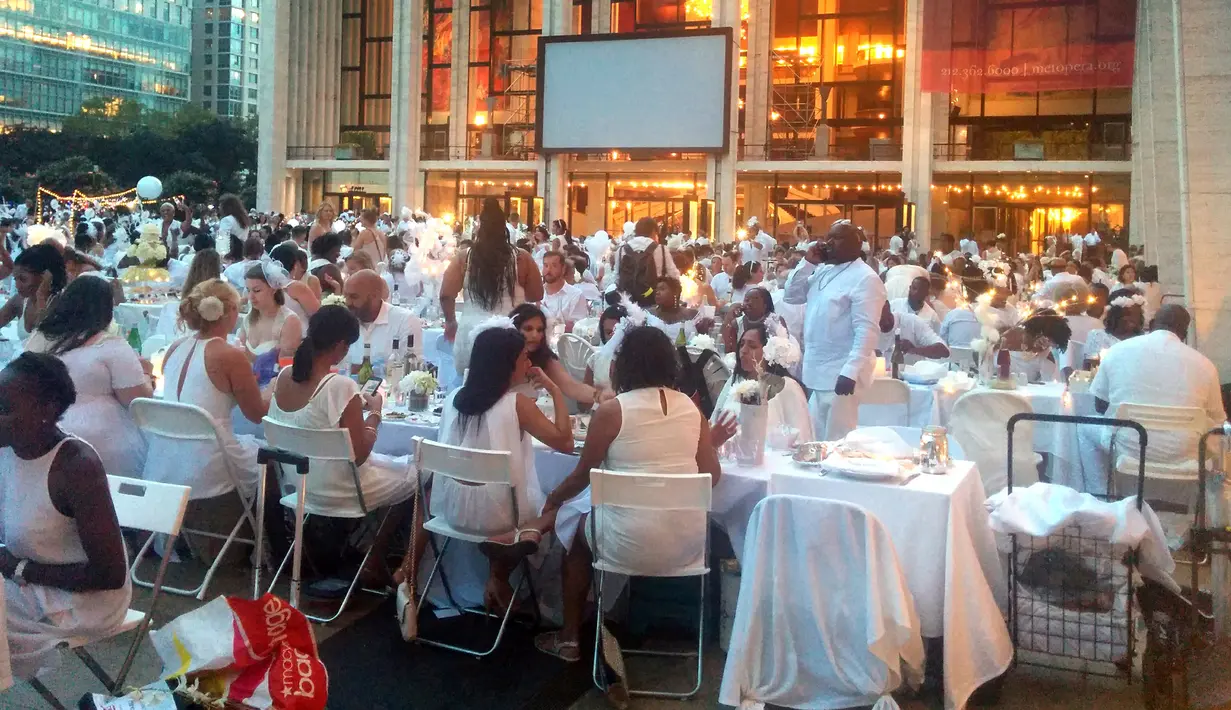 Para tamu melakukan makan malam bersama dalam Diner en blanc  di alun-alun Lincoln Center, New York, Selasa (22/8). Untuk mendapatkan undangan acara ini, peserta diharuskan mengenal salah seorang anggota organisasi Diner en Blanc. (AP Photo/Julie Walker)