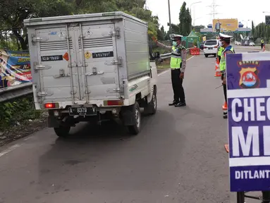 Petugas kepolisian melakukan pengecekan terhadap kendaraan yang keluar Tol Merak, Banten, Senin (18/5/2020). Pemeriksaan (check point) tersebut terkait larangan mudik guna penyekatan atau memeriksa kemungkinan pemudik yang akan keluar dari wilayah Jabodetabek. (Liputan6.com/Angga Yuniar)