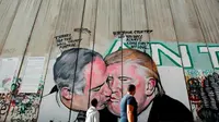 Mural Presiden AS Donald Trump berciuman dengan PM Israel Benjamin Netanyahu di tembok pembatas di Tepi Barat Yerusalem. Mural tersebut karya seniman Australia, Lushux (AFP/Musa Al Shaer)