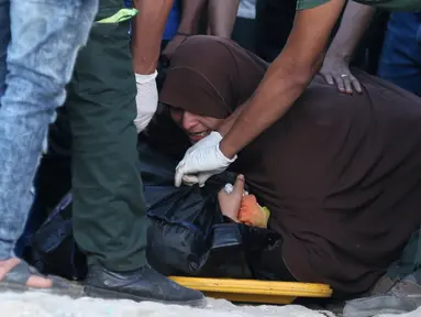 Seorang wanita menangis disamping tubuh anaknya tewas dalam insiden tenggelamnya perahu yang mengangkut ratusan imigran di Al-Beheira, Mesir, (22/9). Setidaknya 52 penumpang ditemukan tewas dan ratusan lainnya masih hilang. (REUTERS/Mohamed Abd El Ghany)