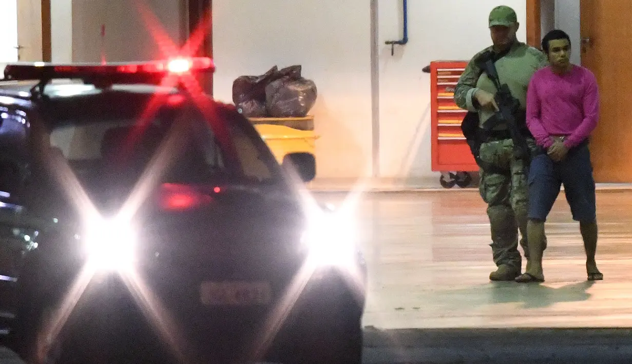 Polisi Brasil mengawal terduga teroris di hanggar Polisi Federal Brasil di bandara di Brasil, (21/7). 10 Orang terduga teroris itu berencana untuk menyerang pelaksanaan Olimpiade Brasil. ( AFP PHOTO/Evaristo SA)