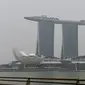 Seorang pria mengambil gambar ketika Hotel dan Resor Marina Bay Sands diselimuti kabut asap, Singapura, Rabu (18/9/2019). Badan Meteorologi Klimatologi dan Geofisika (BMKG) mendeteksi sebaran asap akibat kebakaran hutan dan lahan di Sumatra mencapai Singapura dan Malaysia. (Roslan RAHMAN/AFP)