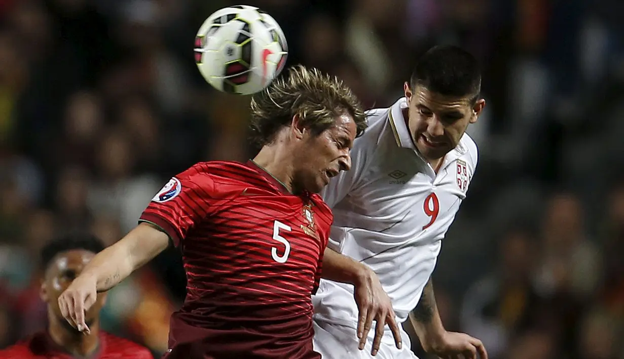Penyerang Serbia, Aleksandar Mitrovic berebut bola udara dengan bek Portugal Fabio Coentrao pada kualifikasi Piala Eropa 2016 di stadion Luz, Lisbon, Minggu (29/3/2015). Portugal menang 2-1 atas Georgia. (REUTERS/Rafael Marchante)