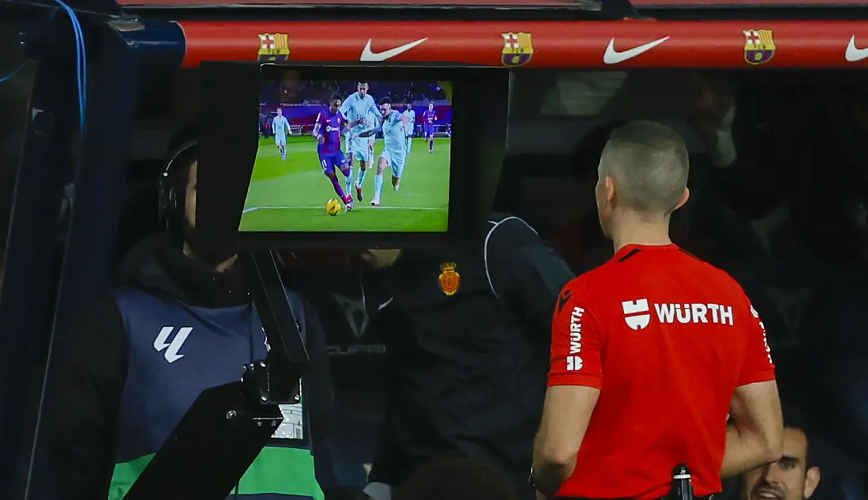 Wasit Javier Iglesias Villanueva memeriksa rekaman VAR sebelum memutuskan memberi hadiah tendangan penalti kepada Barcelona saat menghadapi Mallorca pada laga pekan ke-28 LaLiga 2023/2024 yang berlangsung di Olimpic Lluis Companys Stadium, Barcelona, Sabtu (9/3/2024) dini hari WIB. (AP Photo/Joan Monfort)