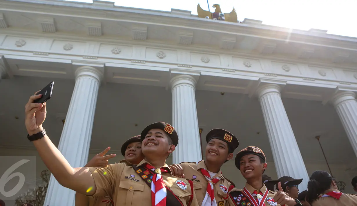  Seorang Pria asik berfoto dengan teman – temannya di Halaman Istana Merdeka, Jakarta, Jumat (24/7/2015). Presiden Jokowi melepas 462 kontingen Pramuka Indonesia ke jepang untuk berkiprah di Jambore Dunia ke-23. (Liputan6.com/Faizal Fanani)