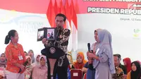 Presiden Joko Widodo atau Jokowi menunjukkan foto saat menyalurkan bantuan sosial Program Keluarga Harapan (PKH) dan Bantuan Pangan Non Tunai (BPNT) kepada seribu warga Depok, Jawa Barat, Selasa (12/2). (Liputan6.com/Herman Zakharia)