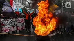 Mahasiswa membakar ban bekas saat demo menolak kenaikan harga Bahan Bakar Minyak (BBM) di kawasan Patung Kuda, Jakarta Pusat (Jakpus), Kamis (8/9/2022). Massa membentuk lingkaran dan menyaksikan ban terbakar. Asap hitam mengepul begitu ban dibakar. (Liputan6.com/Johan Tallo)