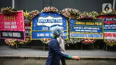 Pekerja melintas di depan karangan bunga untuk Cristalino David Ozora di Rumah Sakit (RS) Mayapada, Kuningan, Jakarta, Selasa (28/2/2023). Sejumlah karangan bunga dikirimkan sebagai bentuk simpati terhadap David Ozora usai mengalami penganiayaan oleh Mario Dandy Satriyo, anak pejabat pajak, Rafael Alun Trisambodo hingga koma. (Liputan6.com/Faizal Fanani)