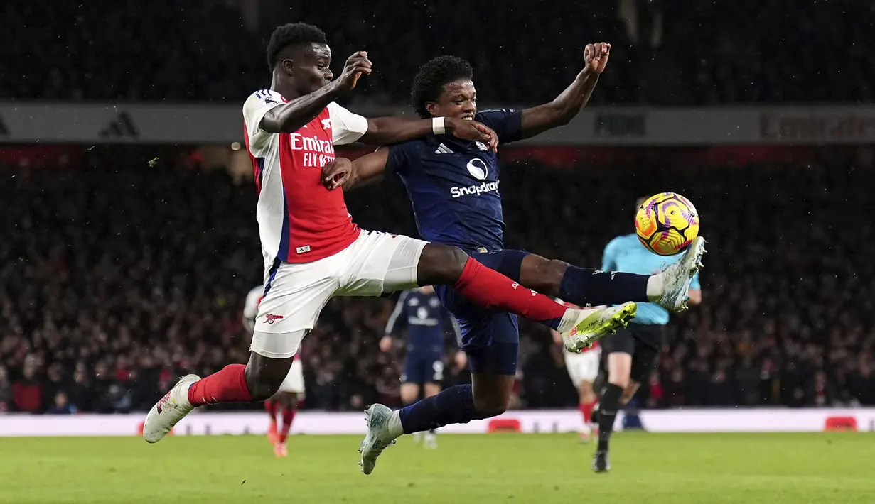 Pemain Arsenal, Bukayo Saka (kiri) berebut bola dengan pemain Arsenal, Tyrell Malacia pada laga lanjutan Liga Inggris 2024/2025 di Emirates Stadium, London, Inggris, Kamis (05/12/2024) WIB. (AP Photo/Kirsty Wigglesworth)