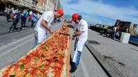 Sejumlah koki ahli berupaya mencetak rekor dunia dengan membuat pizza terpanjang di dunia, di sepanjang pinggir Laut Naples, Italia, 18 Mei 2016. Pizza itu memiliki ukuran sekitar 1 mil dan terbentang di sepanjang pinggir Laut Naples. (Mario LAPORTA/AFP)