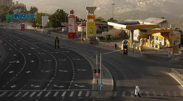 Seorang pria mengenakan syal sembahyang berjalan melintasi jalan utama saat peringatan Yom Kippur, atau Hari Pendamaian, yang berlangsung ketika Israel memberlakukan penguncian nasional (lockdown) selama tiga minggu, di Yerusalem pada Senin (28/9/2020). (AP Photo/Maya Alleruzzo)