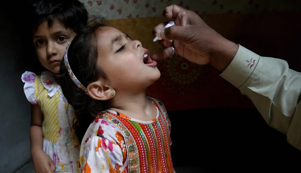 Seorang anak msaat diberikan vaksin polio oleh pekerja kesehatan di Lahore, Pakistan, (9/4). Pakistan meluncurkan vaksinasi polio baru, yang bertujuan agar 38,7 juta anak di bawah usia 5 tahun mendapatkan vaksin tersebut. (AP Photo/KM Chaudary)
