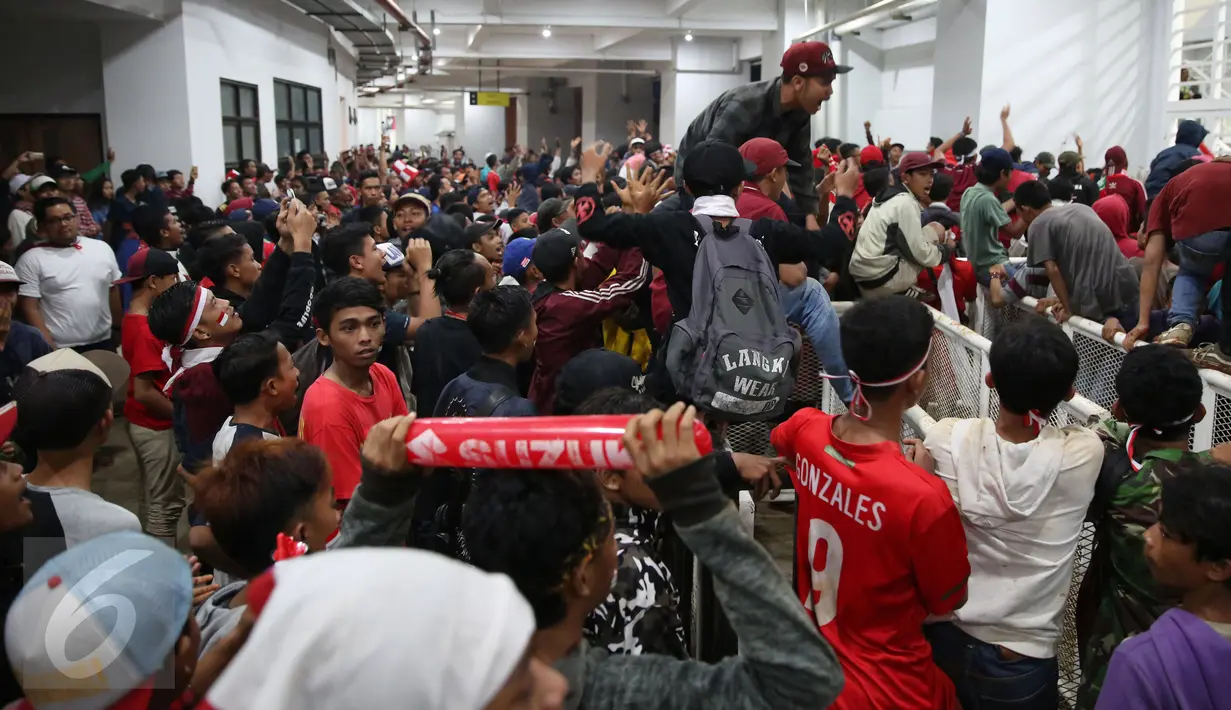 Pendukung Timnas Indonesia memaksa masuk ke dalam tribun saat berlangsungnya leg pertama final Piala AFF 2016 di Stadion Pakansari, Bogor, Rabu (14/12). Kapasitas tribun yang sudah penuh membuat petugas jaga menutup pintu masuk. (Liputan6.com/Johan Tallo)