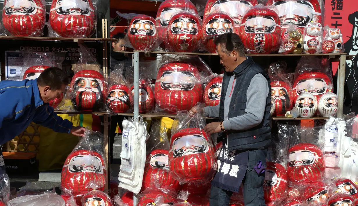 Pedagang boneka merah Daruma dalam pameran tahunan Oume Daruma di Tokyo, 12 Januari 2018. Mereka yang membeli boneka ini bisa melukis di salah satu bola matanya sambil membuat keinginan, dan satu mata lain jika keinginannya terwujud. (AP/Koji Sasahara)
