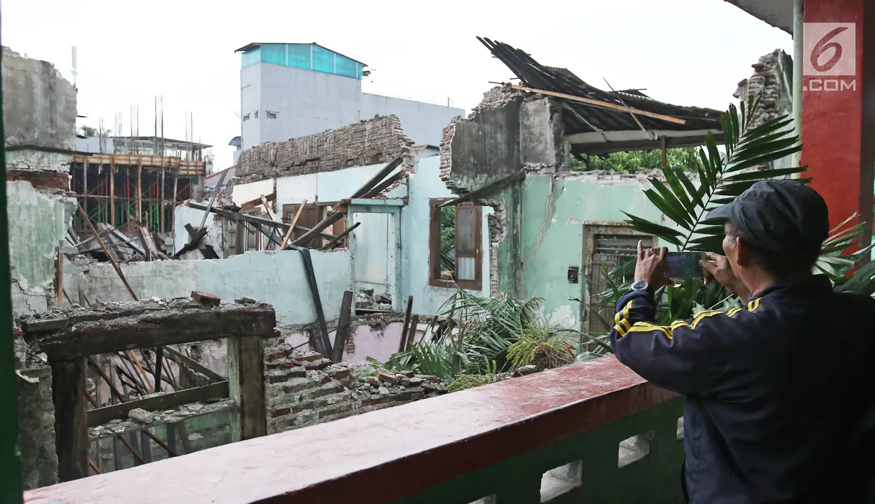 Seorang pria mengambil gambar reruntuhan bangungan SMPN 32 Pekojan Jakarta Barat yang roboh pada Kamis (21/12). Akibat peristiwa ini, dikabarkan tiga orang terluka. Dua di antaranya terkena serpihan reruntuhan bangunan. (Liputan6.com/Herman Zakharia)