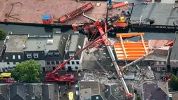Sebuah gambar menunjukkan mesin derek yang jatuh ke rumah warga di Alphen aan den Rijn, Belanda, Senin (3/8/2015). Dua mesin derek yang sedang memperbaiki jembatan ambruk ke rumah yang ada di dekatnya dan melukai 20 orang. (AFP PHOTO/ANP/LEX VAN LIESHOUT)