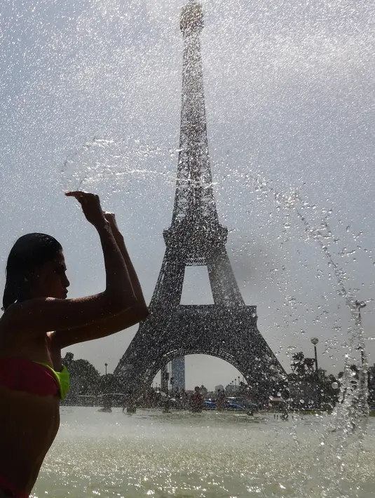 Seorang wanita mendinginkan diri di kolam Trocadero Fountains (air mancur Trocadero) dekat Menara Eiffel di Paris, Kamis (25/7/2019). Gelombang panas di Eropa mencapai puncaknya, bahkan suhu di ibu kota Prancis mencapai di atas 41 derajat Celcius. (Dominique FAGET / AFP)
