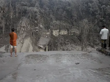 Warga melihat jembatan yang rusak akibat abu vulkanik pascaerupsi Gunung Semeru di Lumajang, Jawa Timur, 5 Desember 2021. Sebanyak 14 orang meninggal dunia dan 69 mengalami luka-luka akibat erupsi Gunung Semeru. (AP Photo/Hendra Permana)