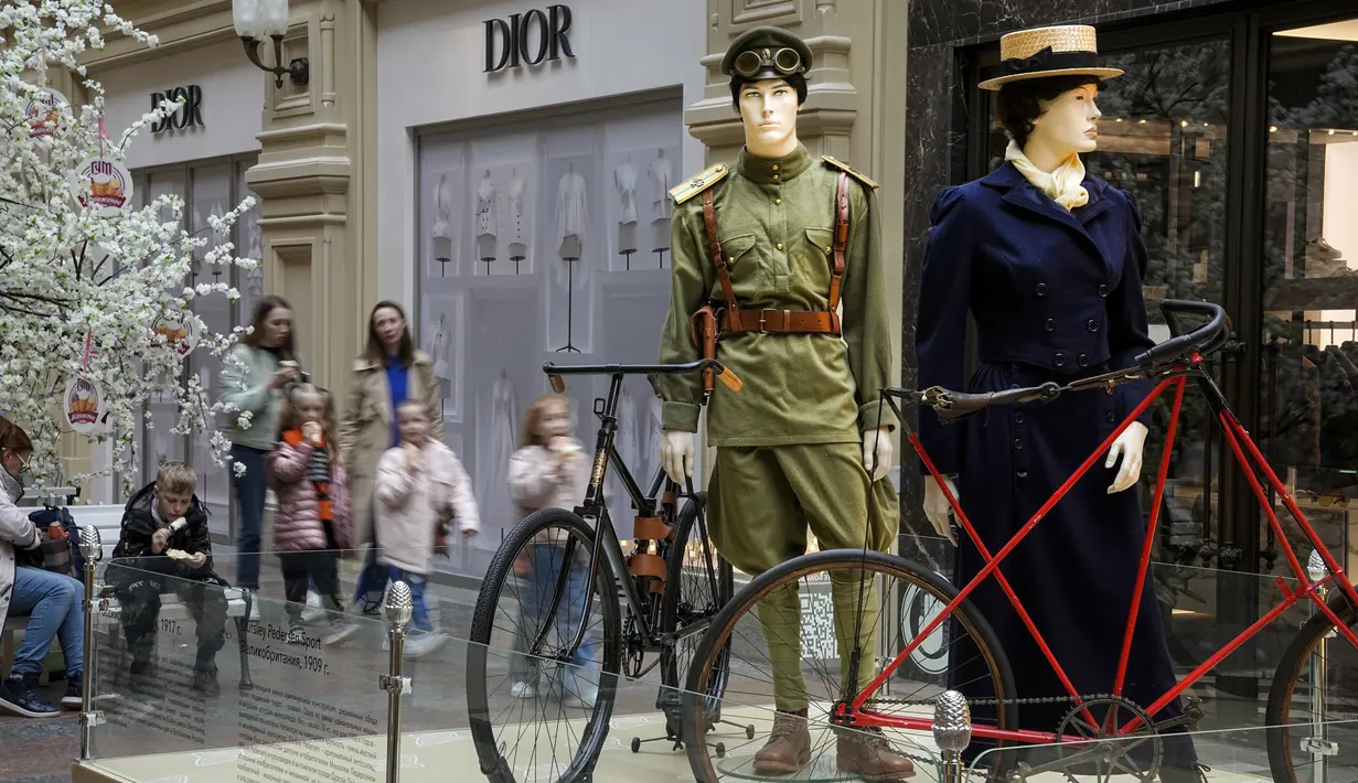 Pengunjung dengan anak-anaknya berjalan di dalam department store GUM dengan butik Dior ditutup karena sanksi sepanjang instalasi sejarah bersepeda di Rusia, di Moskow, Rusia, Selasa, 31 Mei 2022. Ketika invasi Rusia ke Ukraina memasuki hari ke-100, kehidupan di Moskow dan St. Petersburg sebagian besar tetap normal, bahkan ketika banyak pengecer Barat mulai hengkang dari negara itu. (AP Photo/Alexander Zemlianichenko)