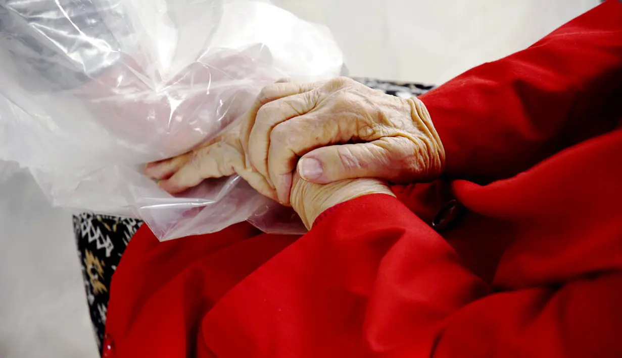 Gregg MacDonald menggenggam tangan ibunya Chloe MacDonald (84) di tenda pelukan di luar pusat bantuan kehidupan Desa Juniper, Louisville, Cololardo, Amerika Serikat, 3 Februari 2021. Di Brasil dan Inggris, orang-orang menyebut tenda pelukan sebagai tirai pelukan. (AP Photo/Thomas Peipert)