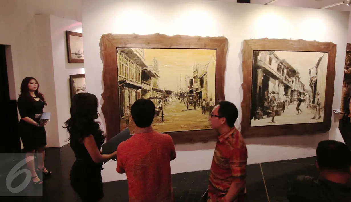 Pekerja menjelaskan sebuah lukisan kepada pengunjung pameran pelukis Soehib Toyaroja bertajuk The Spiritual Journey di Kunstkring Art Galeri, Jakarta, Selasa (15/3). Pameran tersebut dibuka oleh Ketua KEIN, Soetrisno Bachir. (Liputan6.com/Angga Yuniar)