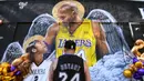 Seorang fans berdiri di depan lukisan mural bintang LA Lakers, Kobe Bryant bersama putrinya, Gianna di Los Angeles, California, Selasa (26/1/2021). Lukisan dibuat untuk mengenang 1 tahun tragedi kecelakaan helikopter yang menewaskan keduanya. (Getty Images via AFP/Harry How)