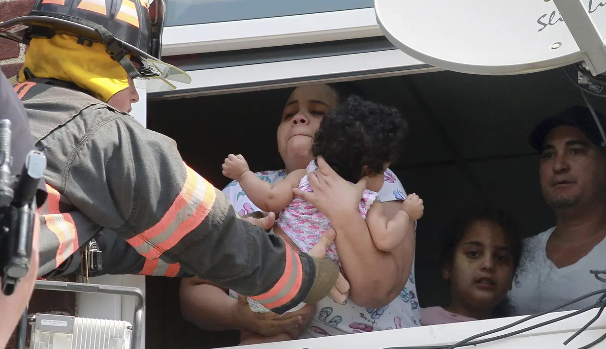 Petugas pemadam kebakaran menyalamatkan bayi setelah kebakaran terjadi di dalam gedung di Hazleton, Pennsylvania (26/7/2019). Restoran dan apartemen Prestigio rusak dilalap api. (Warren Ruda/Hazleton Standard-Speaker via AP)