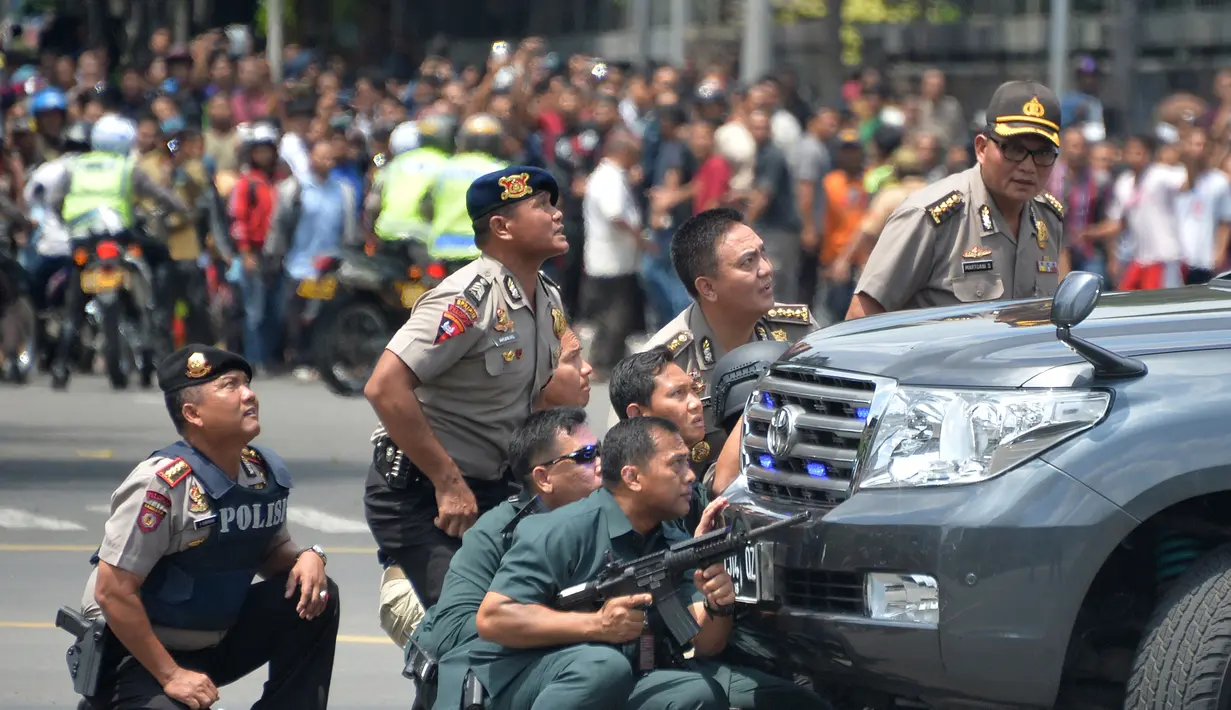Sejumlah polisi mengambil posisi di dekat sebuah mobil saat melakukan pengejaran terhadap pelaku ledakan di pospol Sarinah, Jakarta, Kamis (14/1). Baku tembak terjadi di depan Sarinah setelah suara ledakan ketiga terjadi.  (AFP PHOTO/Bay Ismoyo)