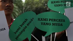 Aktivis Poros Indonesia Muda saat melakukan aksi dengan membawa balon bertempelkan gambar politisi muda di Gedung KPU, Jakarta, Rabu (1/8). Mereka berharap Pemilu 2019 mendapatkan pilihan yang membawa aspirasi kaum muda. (Liputan6.com/Helmi Fithriansyah)