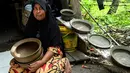 Seorang pembuat tembikar memegang pot tanah liat buatannya dalam bengkel rumah di Banda Aceh, Aceh, Rabu (4/8/2021). (CHAIDEER MAHYUDDIN/AFP)