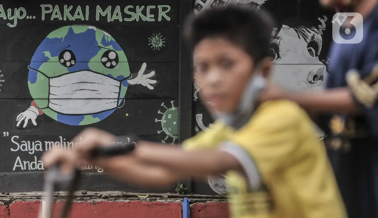 Anak-anak melintasi mural bertemakan Imbauan Protokol Kesehatan Covid-19 di kawasan Bukit Duri, Jakarta, Minggu (25/10/2020). Gubernur DKI Anies Baswedan kembali memperpanjang pelaksanaan PSBB masa transisi sebagai antisiapsi lonjakan kasus virus corona Covid-19. (merdeka.com/Iqbal Nugroho)