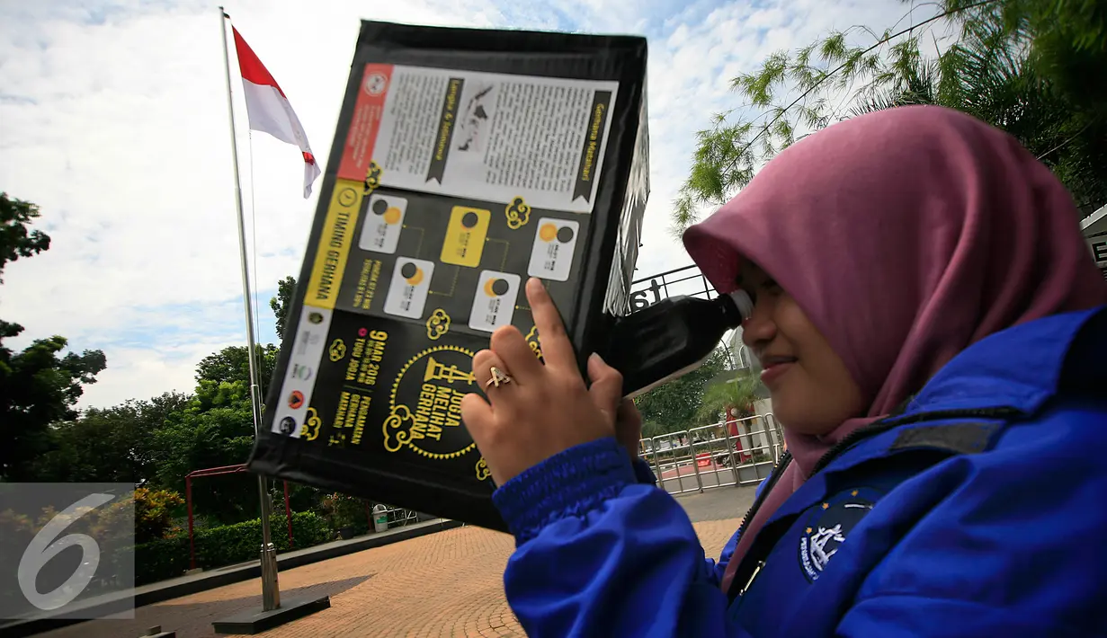 Mahasiswi mencoba peralatan kotak lubang jarum yang akan di gunakan untuk mengamati gerhana matahari di taman Pintar Yogyakarta, (2/3). Kawasan Tugu menjadi salah satu tempat pengamatan gerhana matahari pada 9 Maret 2016. (Liputan6.com/Boy Harjanto)