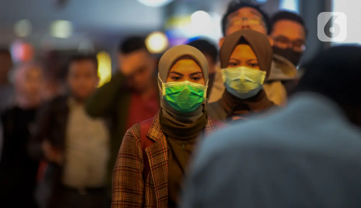 Calon penumpang kereta api mengenakan masker saat berada di Stasiun Gambir, Jakarta Pusat, Jumat (31/01). Dalam rangka pencegahan Virus Corona, PT Kereta Api Indonesia (persero) melakukan sosialisasi kepada penumpang dengan membagi-bagikan masker di stasiun Gambir. (merdeka.com/Imam Buhori)