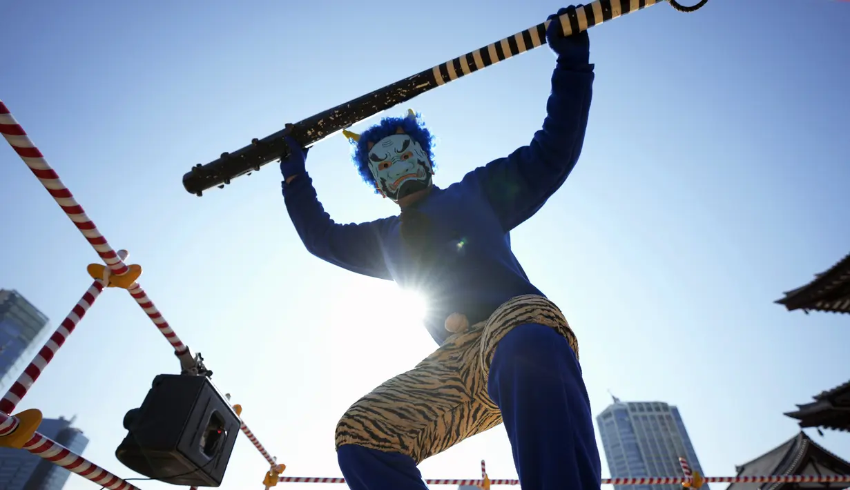 Seorang penampil yang bertindak sebagai setan menari selama "Mame-maki," upacara pelemparan kacang, di kuil Buddha Zojoji di Tokyo, 3 Februari 2022. Ritual yang diyakini membawa keberuntungan dan mengusir kejahatan dilakukan setiap tahun untuk menandai awal musim semi. (AP Photo/Eugene Hoshiko)