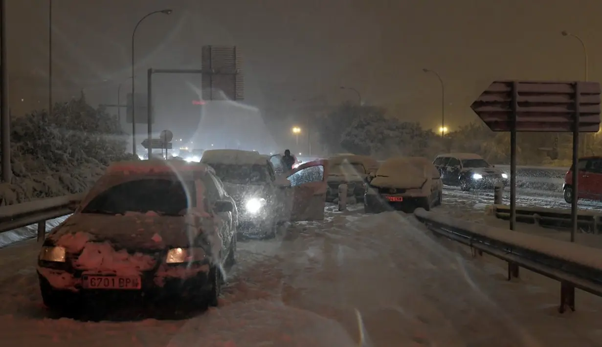 Sejumlah mobil terjebak salju tebal yang menyelimuti Jalan Lingkar M30 di Madrid, Spanyol, Jumat (8/1/2021). Salju tebal memotong dua jalan lingkar di Madrid, M30 dan M40. (OSCAR DEL POZO/AFP)